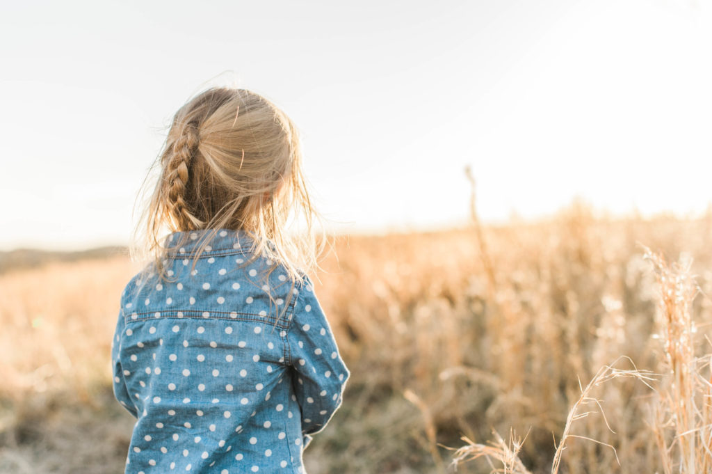 little girl in field at sunset