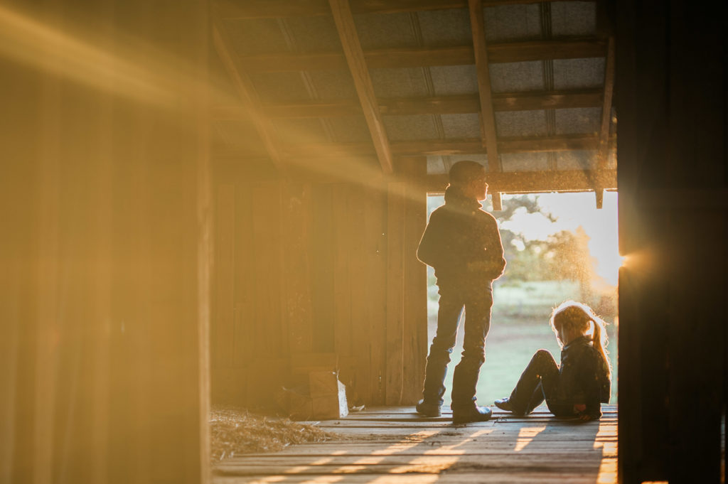 children in barn at sunset